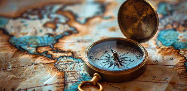 A vintage compass sits on a weathered world map